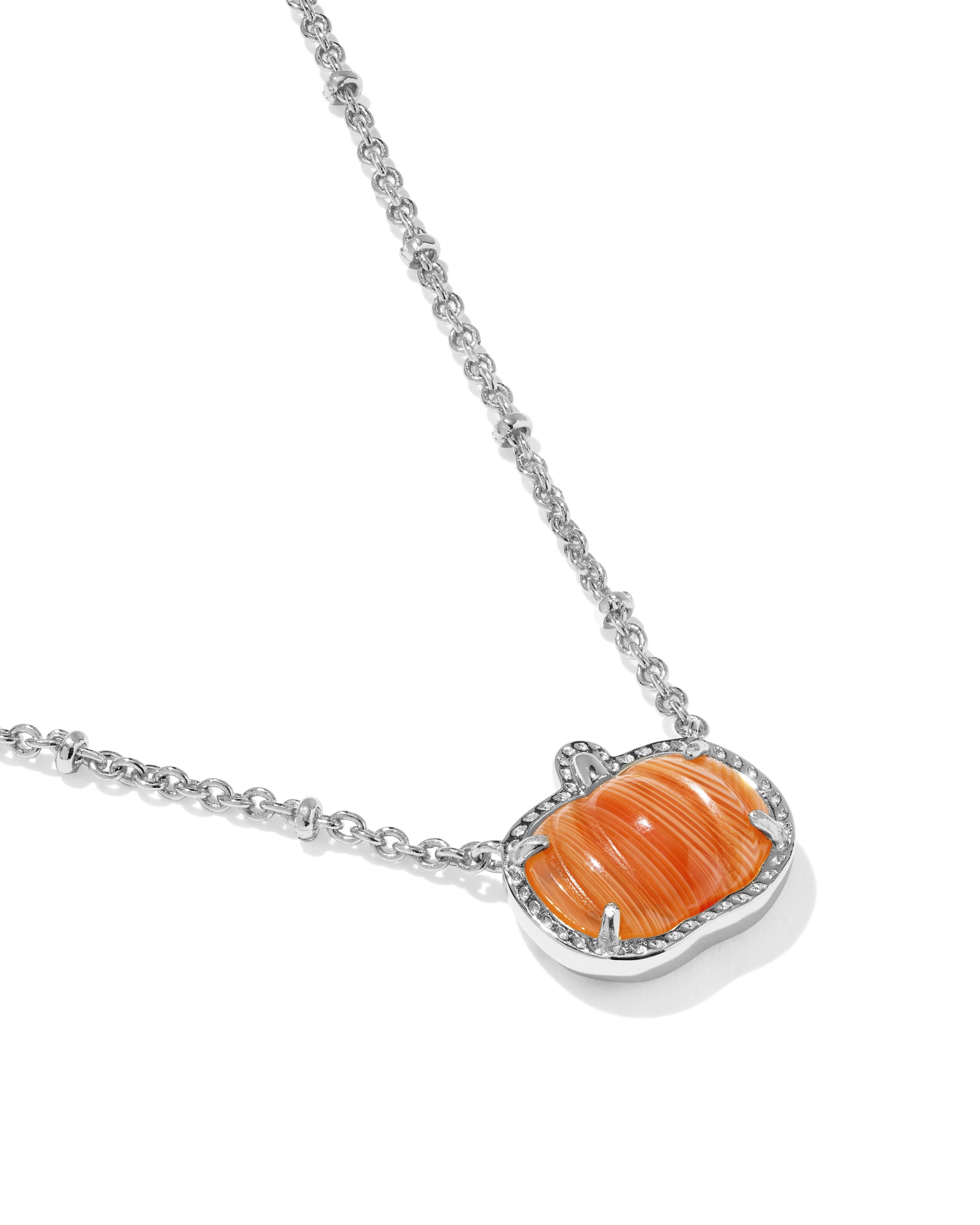 A silver chain necklace featuring a pumpkin-shaped pendant with a carved orange center and a border of small clear stones, shown on a white background.