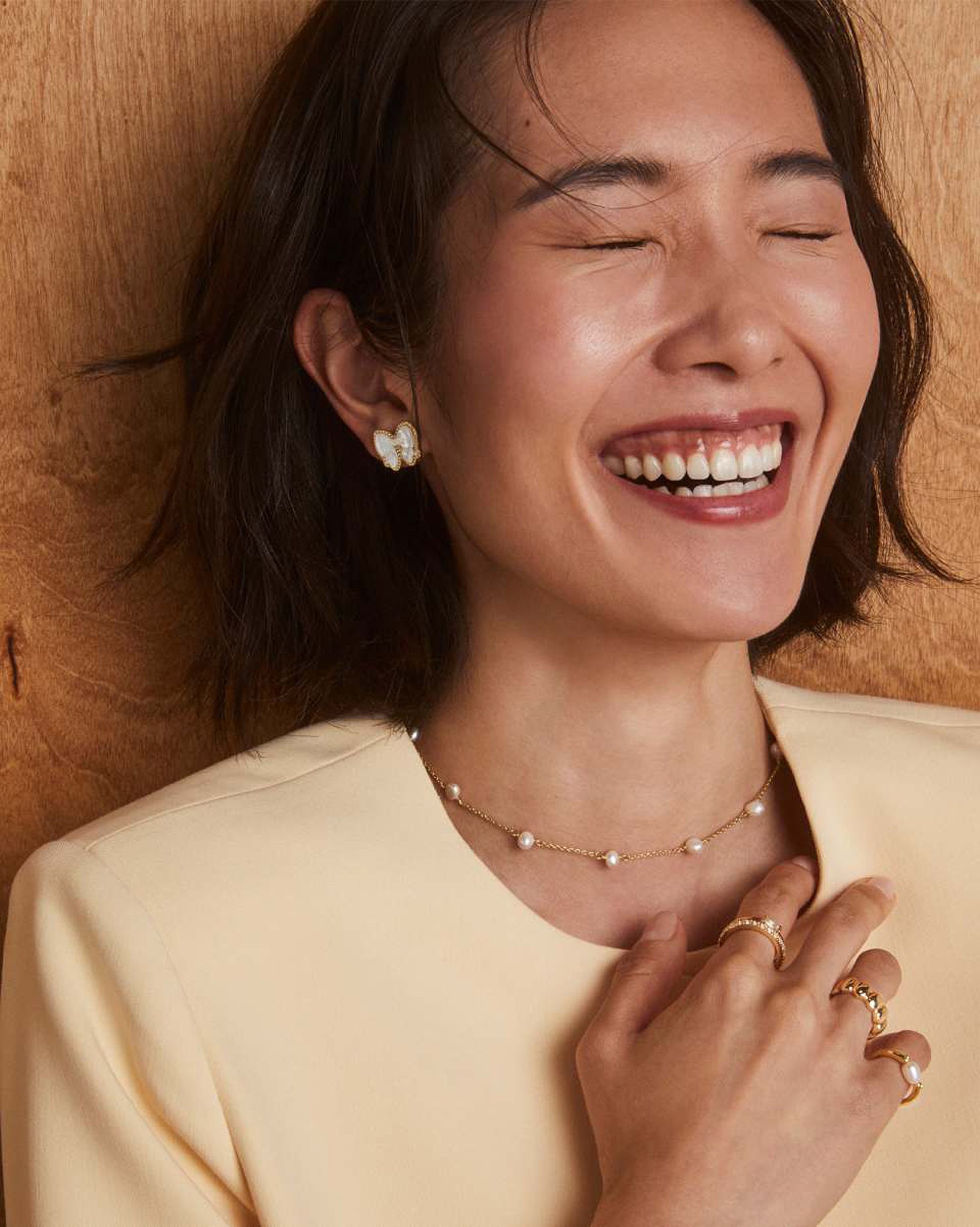 Woman wearing pearl jewelry against a wooden background
