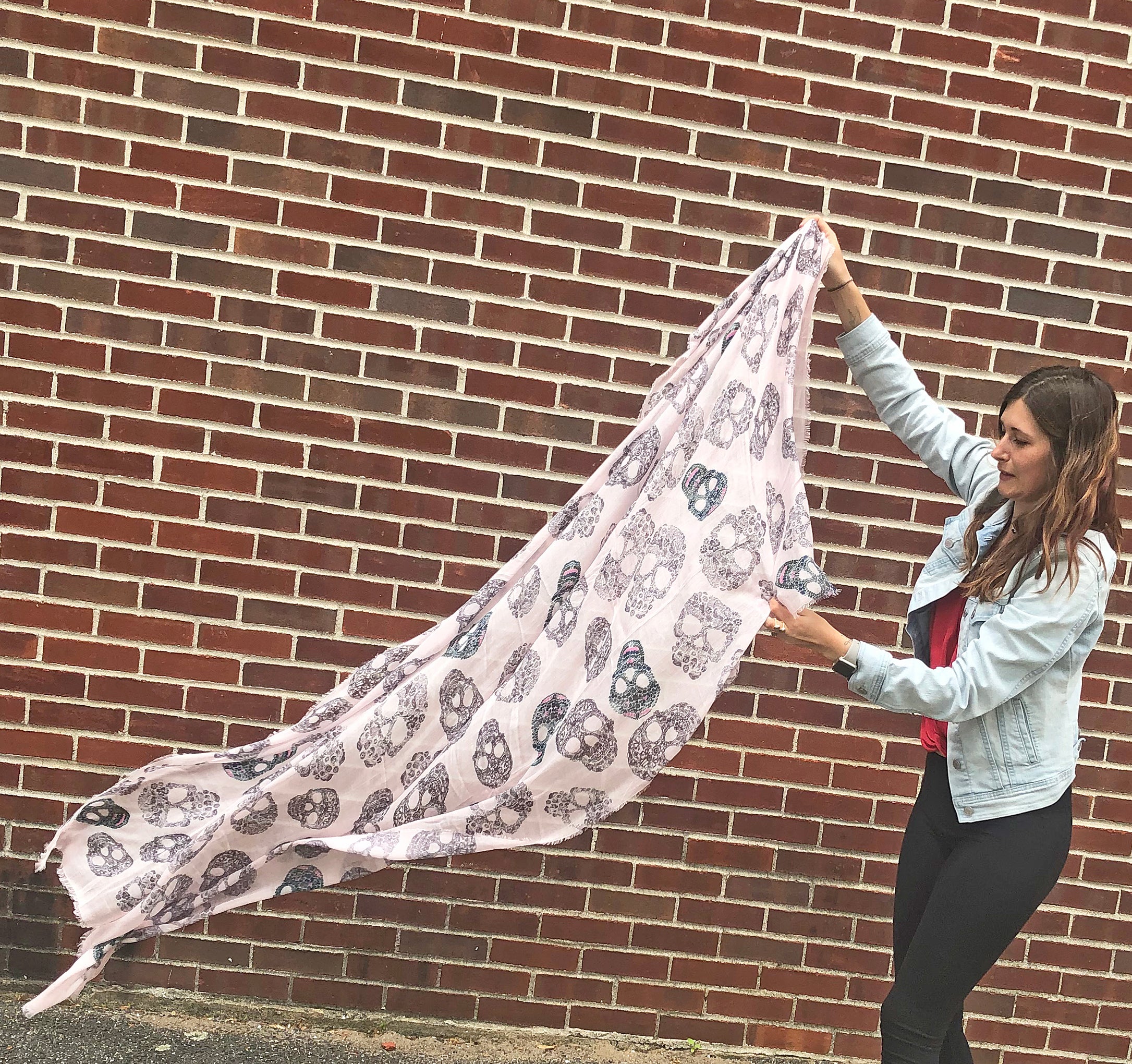model holding Blue Pacific Frida Cashmere and Silk Scarf with Sugar Skulls in Pink